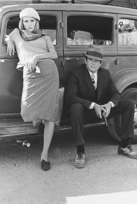 Faye Dunaway as Bonnie Parker and Warren Beatty as Clyde Barrow, wearing hat, both leaning on car and holding guns/pistols.