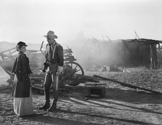 Olivia Dandridge as Joanne Dru and John Wayne as Captain Nathan Brittles, standing by broken-down wagon.