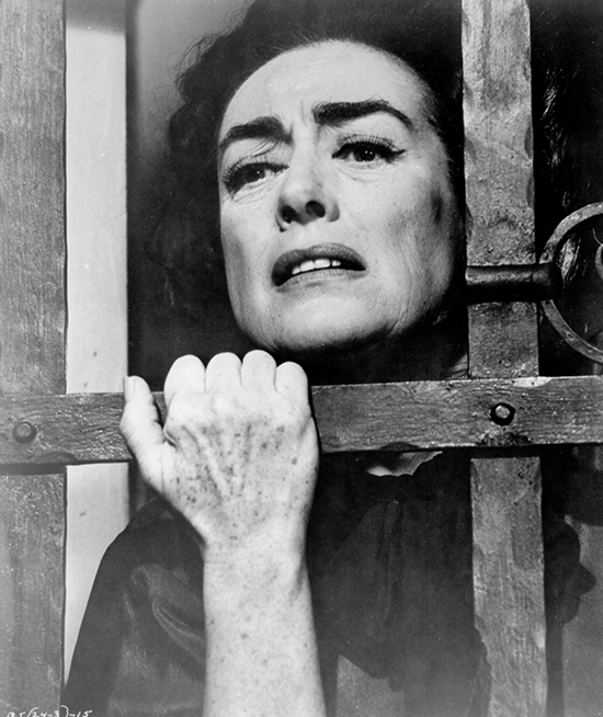 Joan Crawford as Blanche Hudson peering head through bars on window