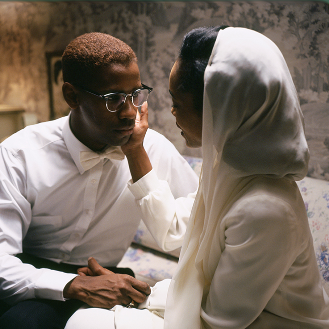 Medium shot of Angela Bassett as Betty Shabazz wearing a white robe and head covering, touching the face of Denzel Washington as Malcolm X.